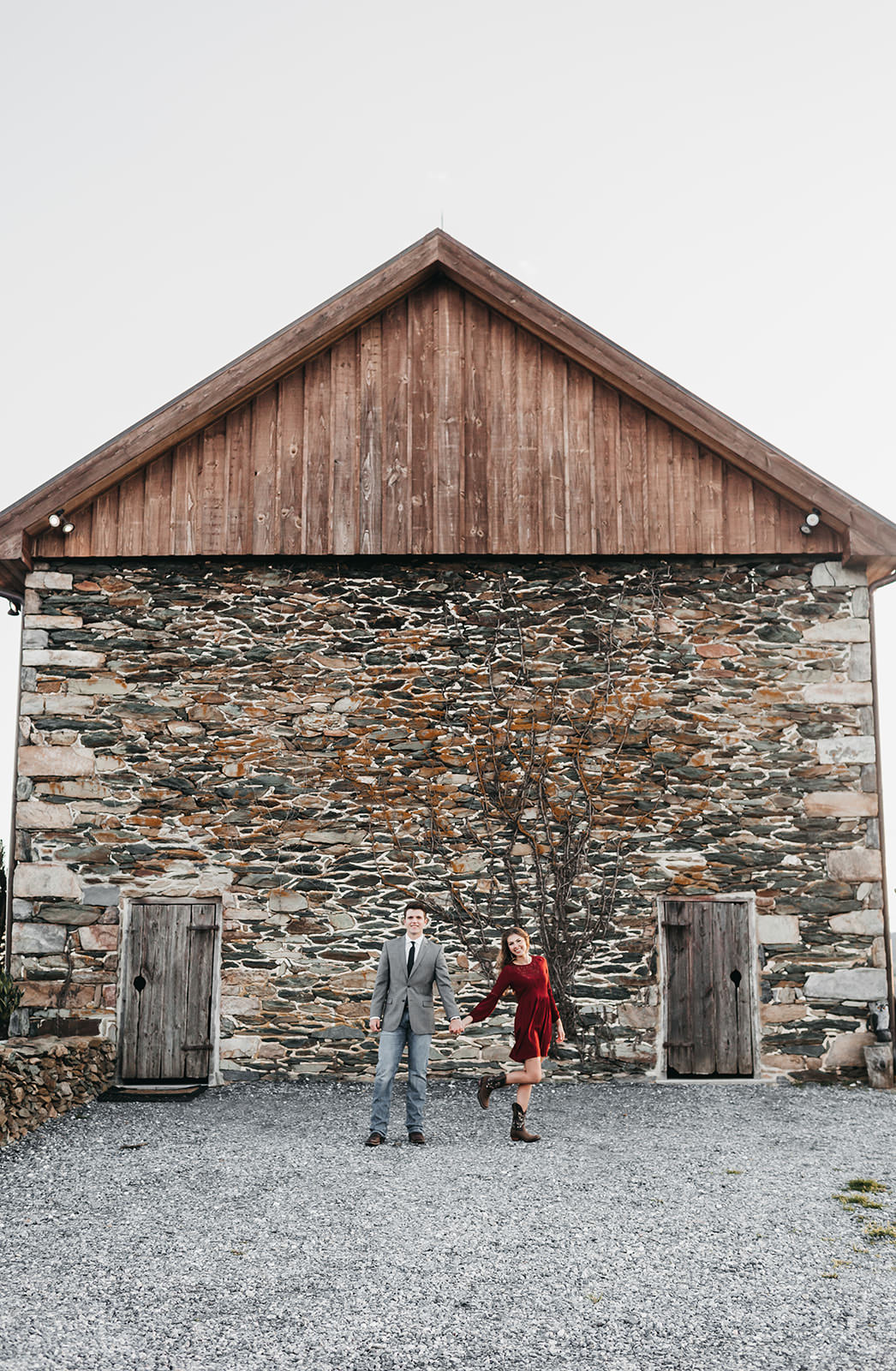 photo of a couple standing in front of a stone wall barn