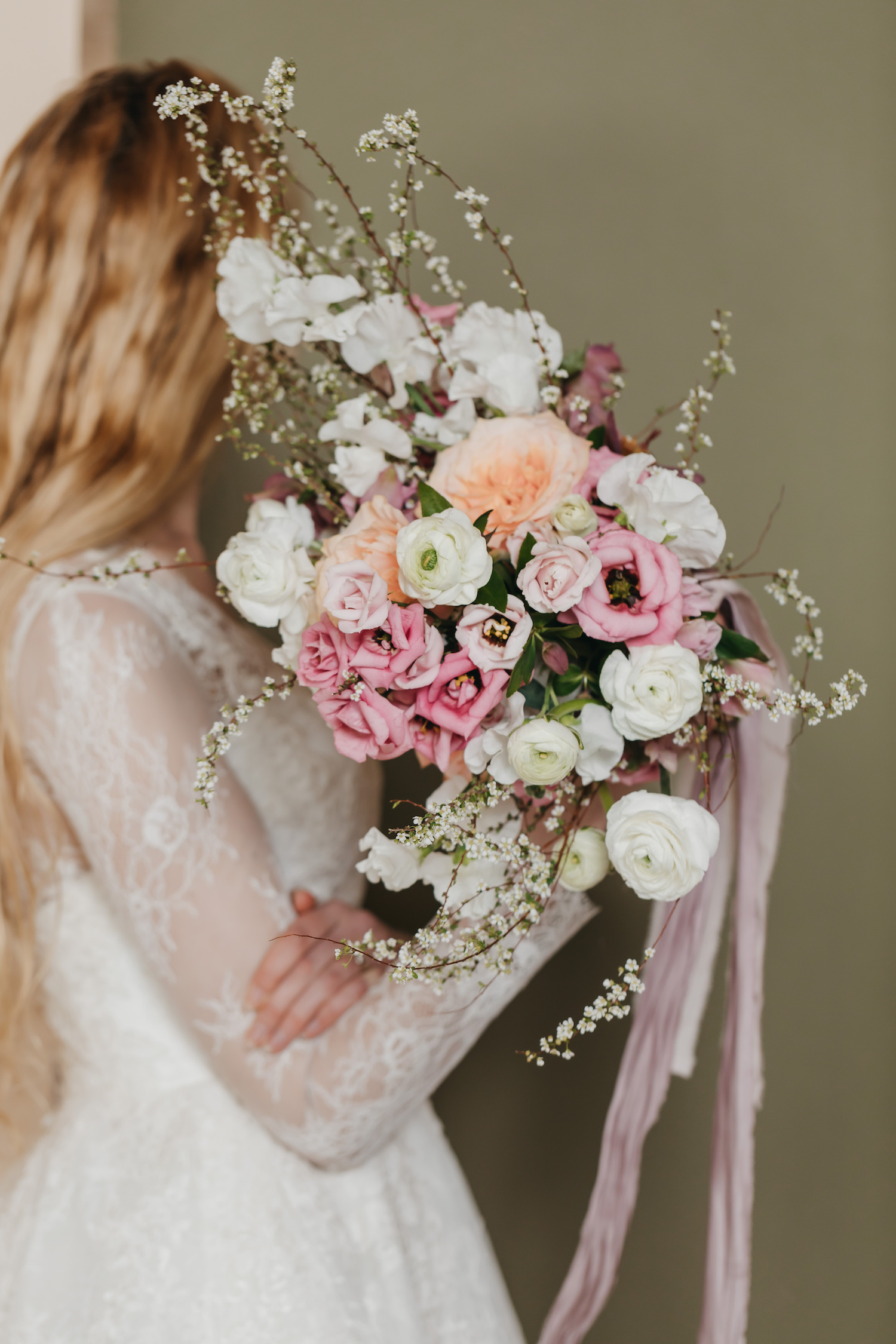 Close-up shot of the bride in her gorgeous lace dress covering her face with her pastel floral bouquet, taken by Rachel Yearick Photography