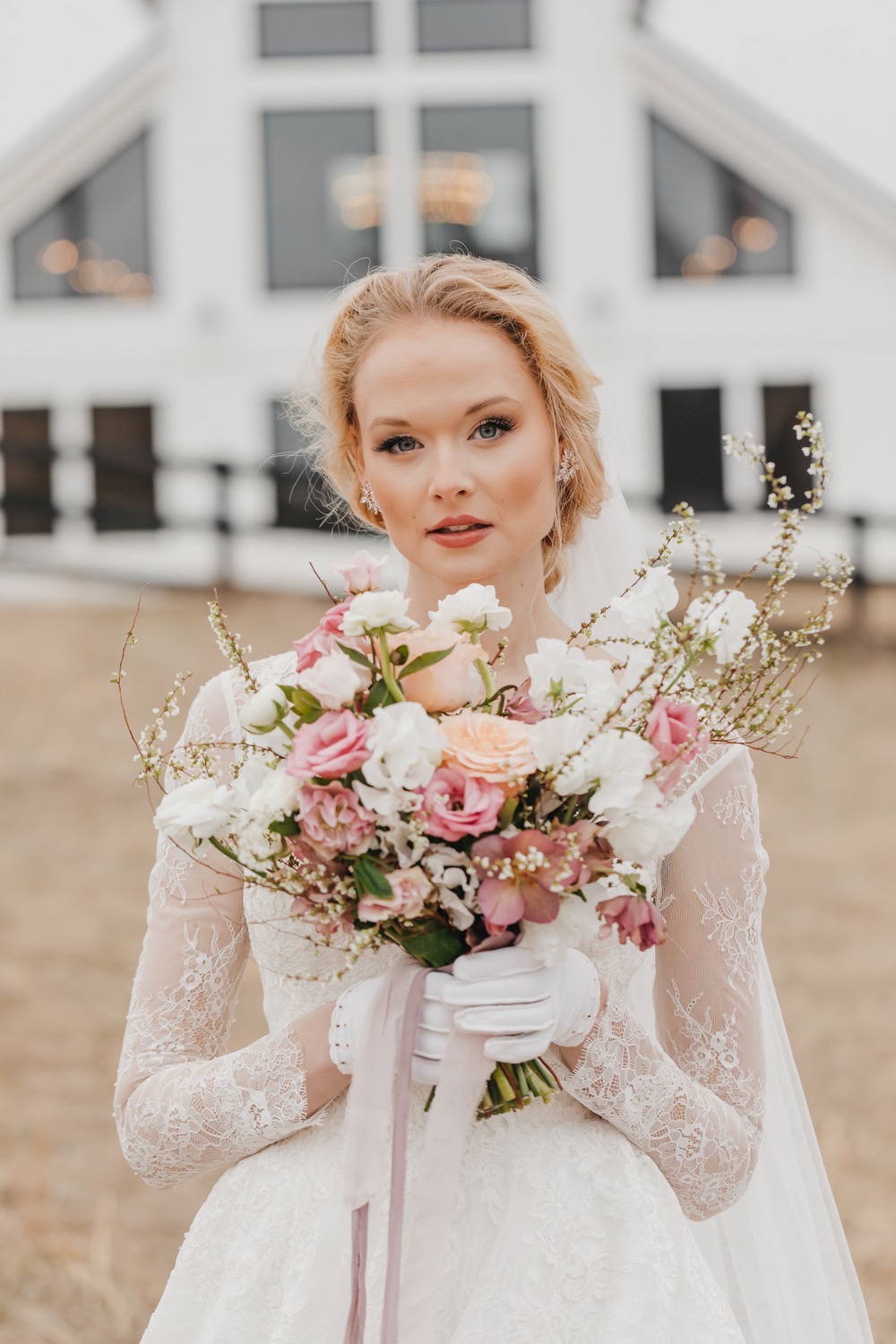 Bride looking intensely at the camera and holding up her floral bouquet at Barn at Willow Brook, taken by Rachel Yearick Photography