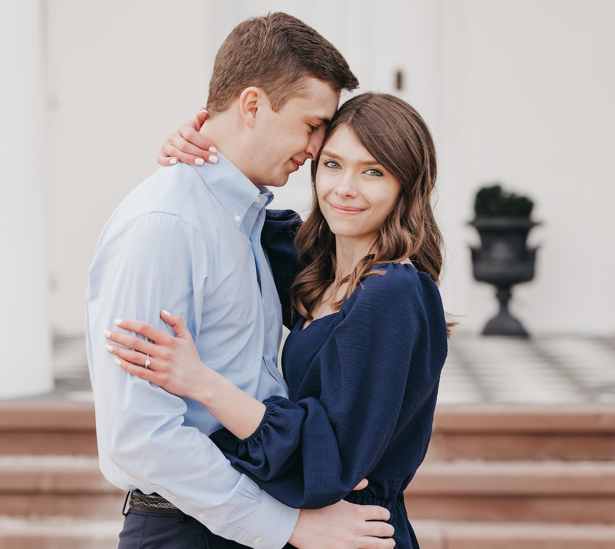 Couple wrapping their arms around each other with the girl smiling at the camera during their engagement shoot with Rachel Yearick Photography