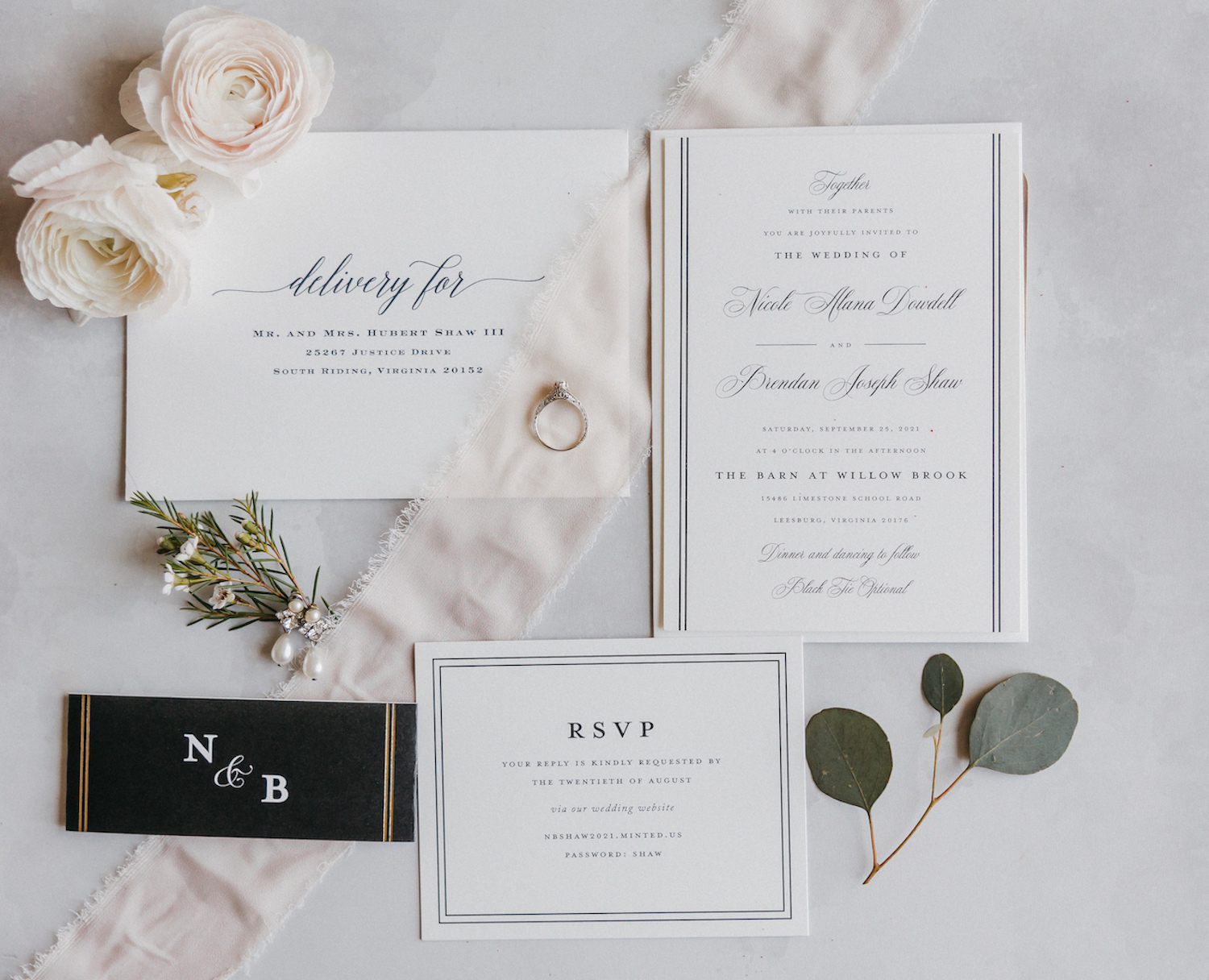 Flat-lay shot of wedding invitations and cards placed beside flowers and plants with a ring in the center, captured by Rachel Yearick Photography