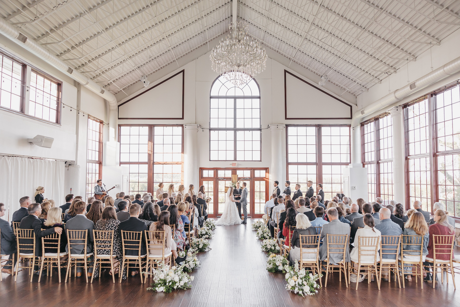 Wedding ceremony with bride and groom at the altar inside a stunning event hall, taken by Rachel Yearick Photography