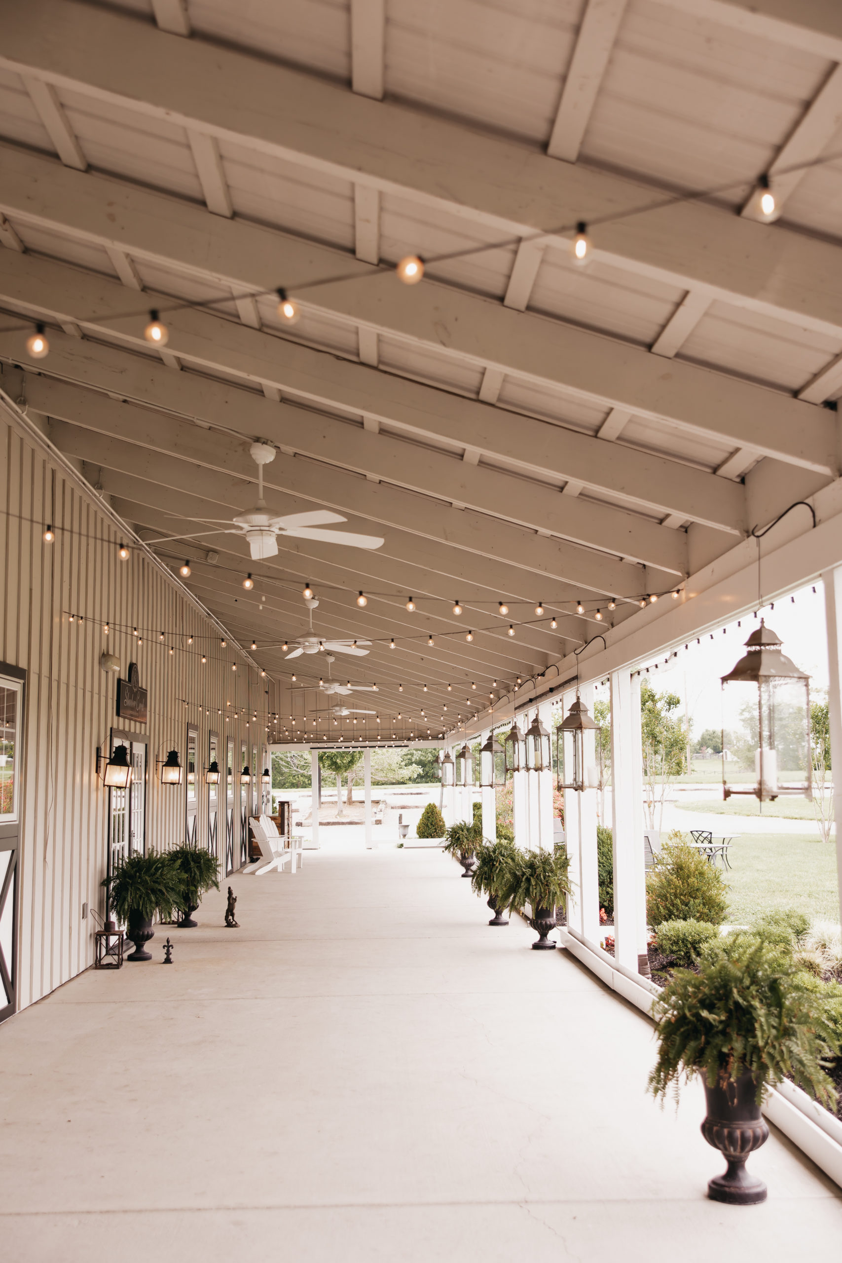 The portico, a charming covered space in front of the barn with string lights, captured by Rachel Yearick Photography