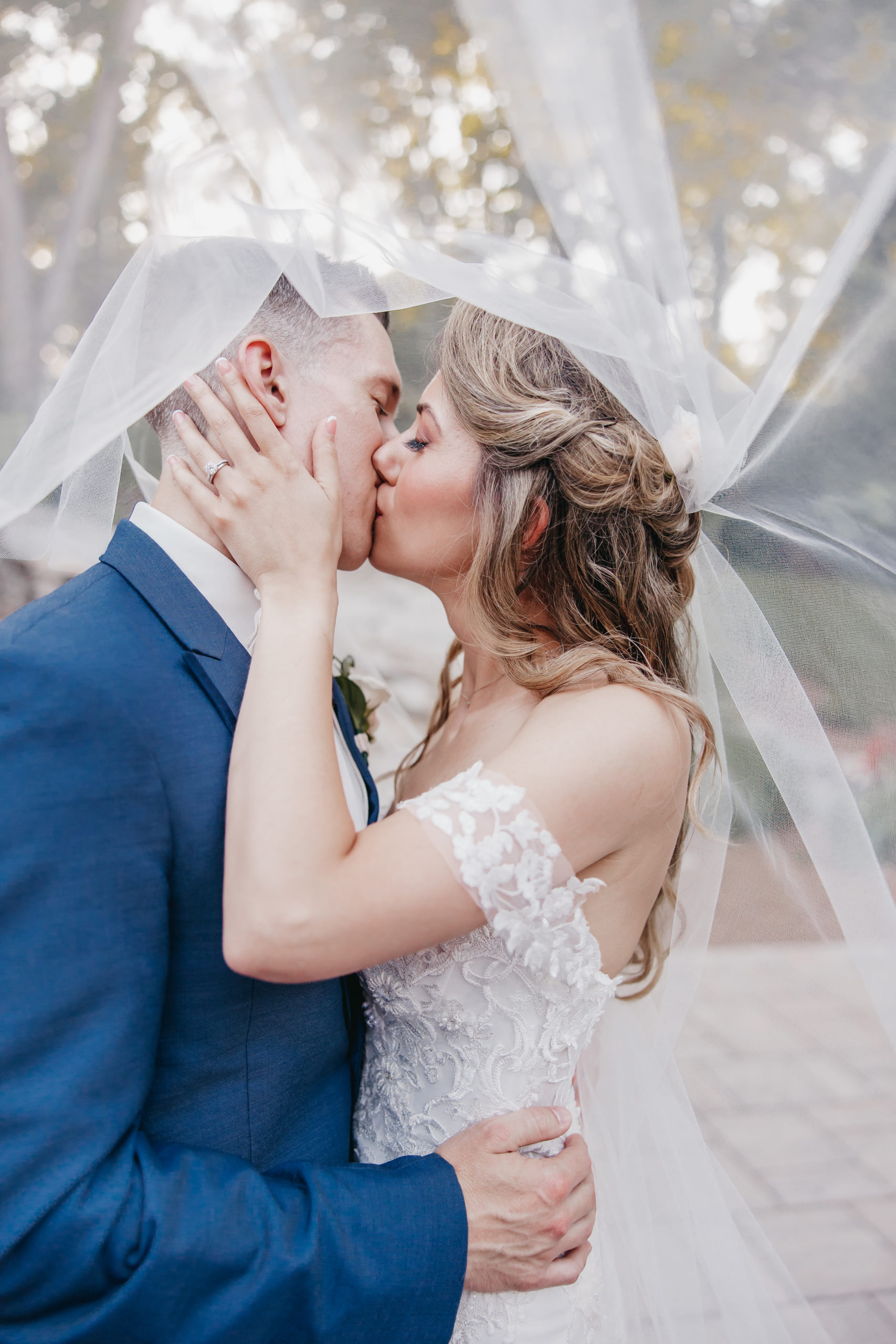 What to Look For When Choosing Between Christian Wedding Photographers. Couple sharing a kiss underneath bride's sheer veil.