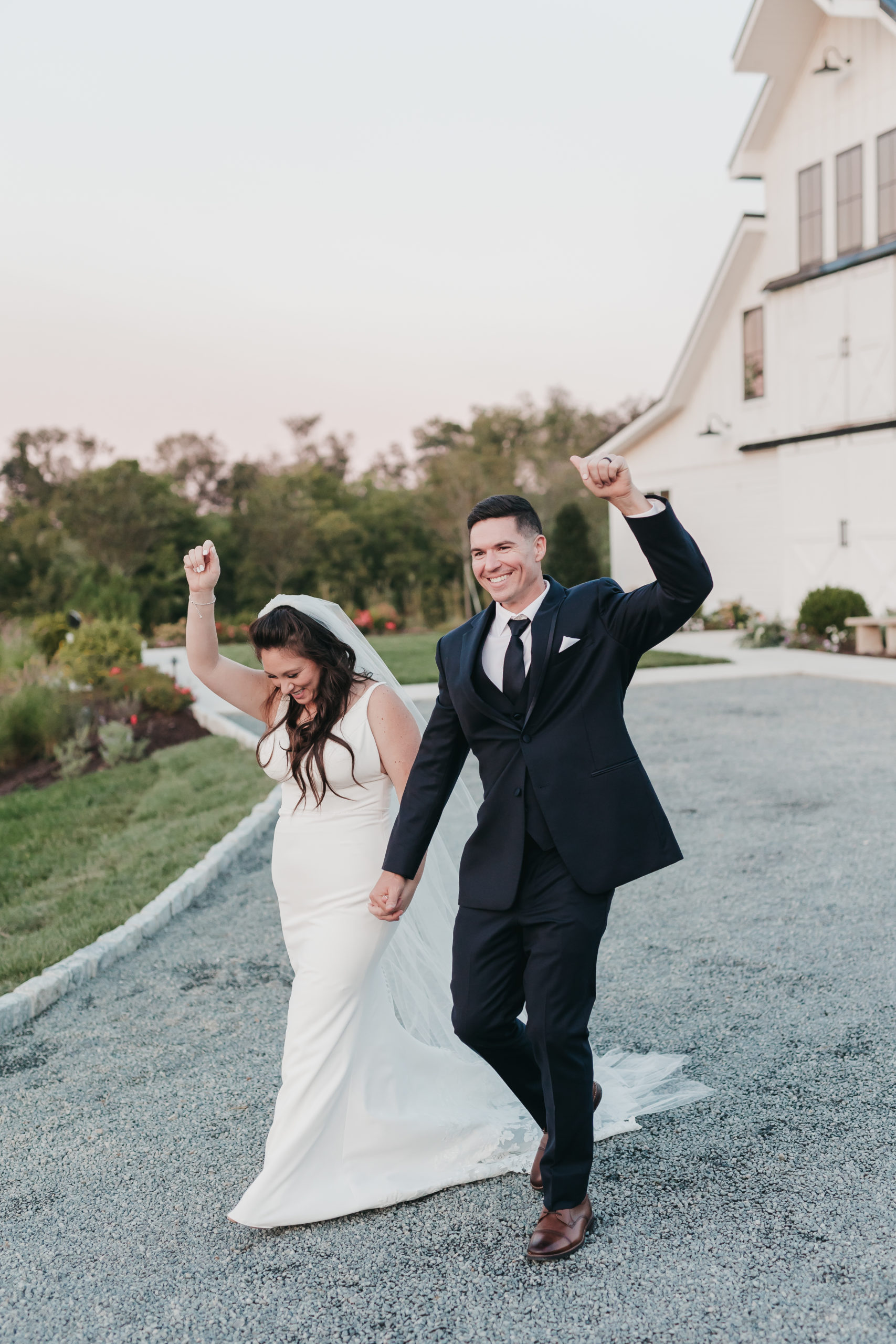Bride and groom raising their hands as they walk and smile around the venue, taken by VA wedding photographer Rachel Yearick