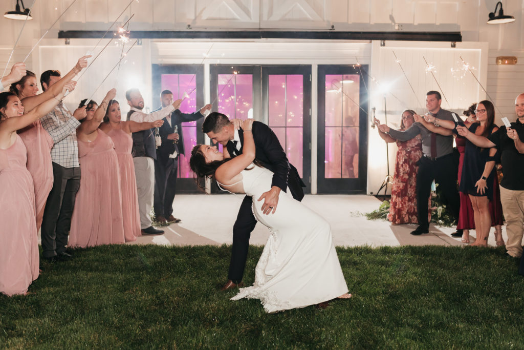 The Barn at Willow Brook Planning And Pricing Guide. Bride and groom leaning in for a kiss as their guests hold up sparklers.
