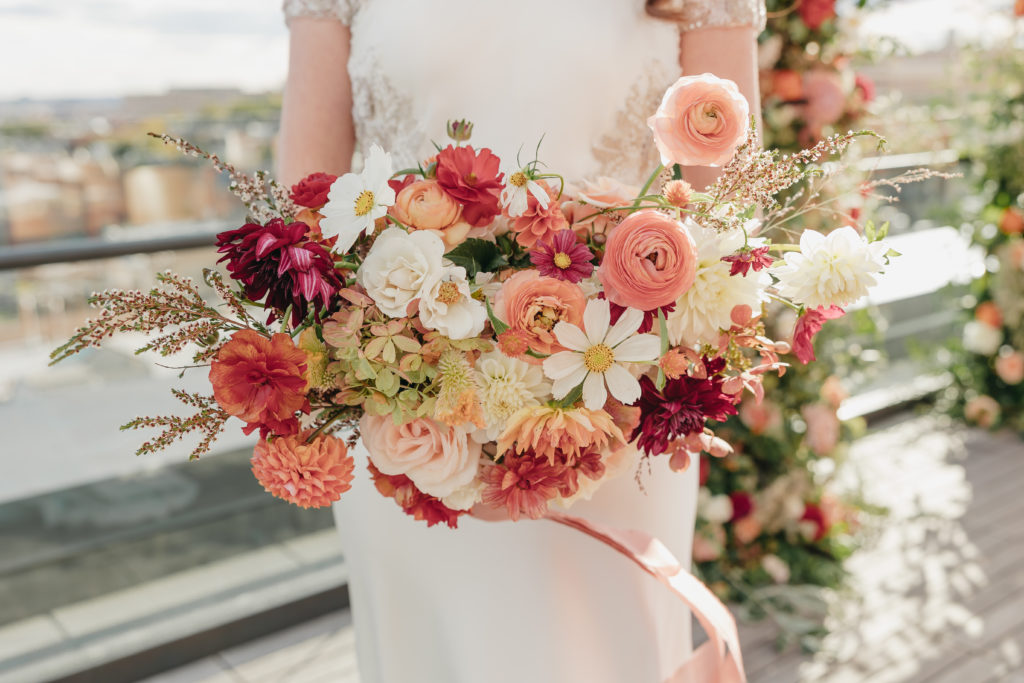 Close-up shot of bride holding up her vibrant bouquet of flowers, captured by VA wedding photographer Rachel Yearick