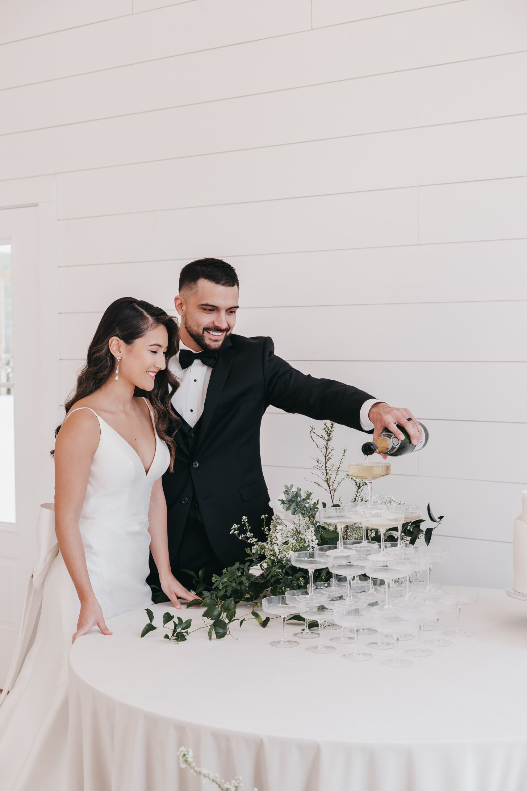 Couple pouring champagne over glasses stacked together, shot by fine art wedding photographer Rachel Yearick