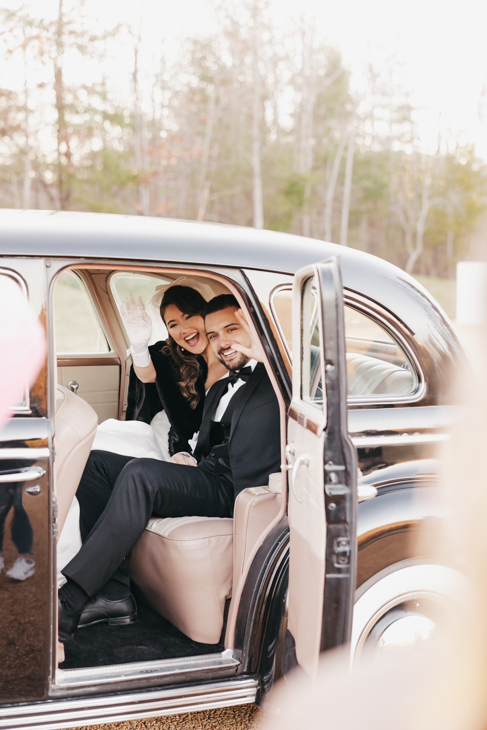 Bride and groom waving goodbye as they sit in the back of a car, taken by Loudoun County wedding photographer Rachel Yearick