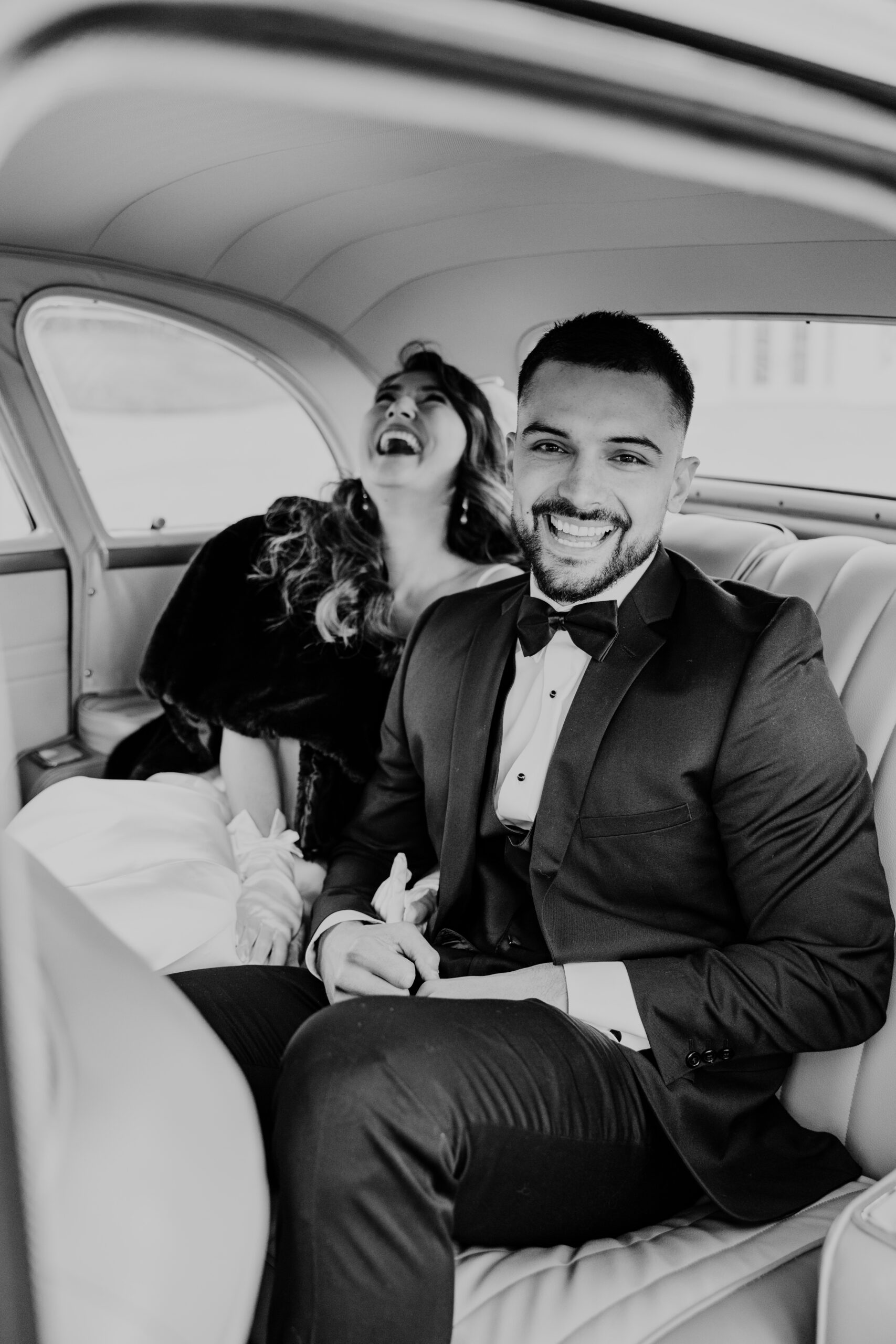 How To Find The Perfect Loudon County Wedding Photographer. Black and white photo of couple laughing in the back of the car.