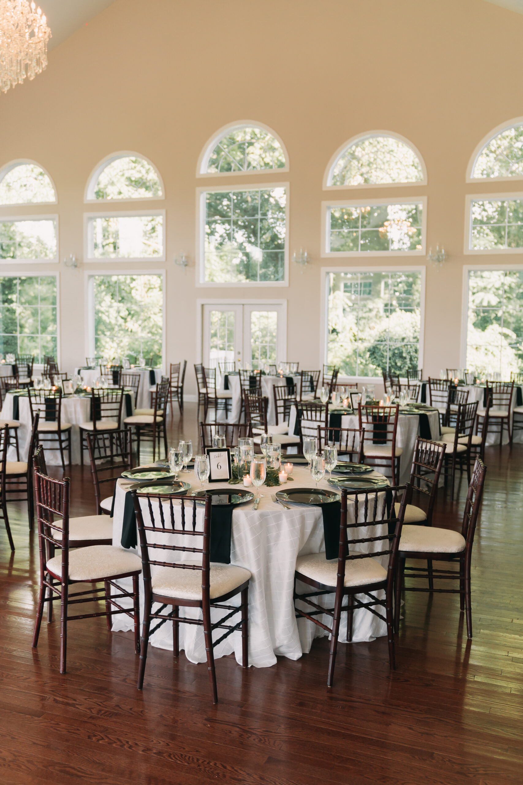 Overview of wedding reception venue with tables and tall windows, taken by Rachel Yearick Photography