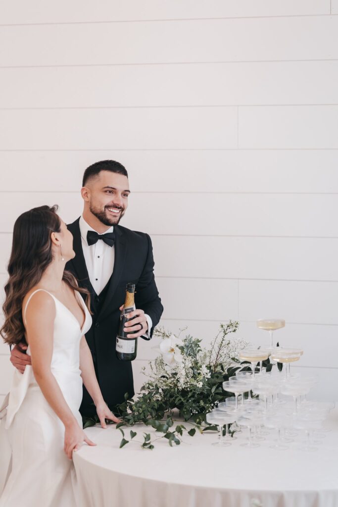 groom smiling while pouring a drink and embracing his bride
