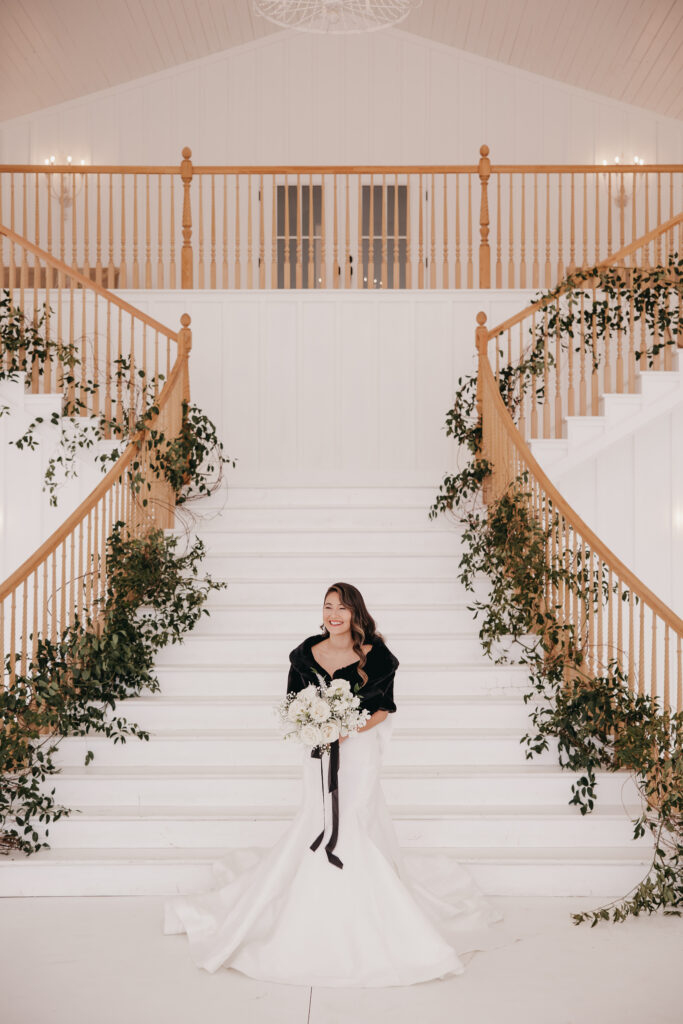 bride smiling in front of the stairs of her wedding venue