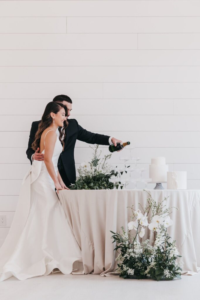 couple pouring Champagne near their simply wedding cake