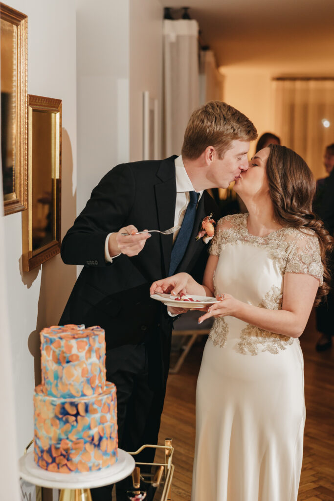 bride and groom kissing after eating their custom wedding cake