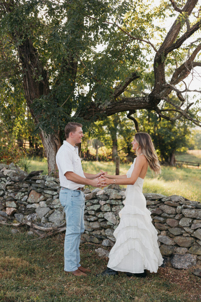 Golden-hour portrait of an engaged couple embracing in an open meadow, surrounded by warm natural light