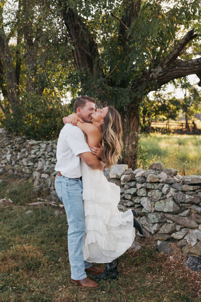 Golden-hour portrait of an engaged couple embracing in an open meadow, surrounded by warm natural light