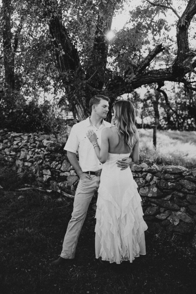 Golden-hour portrait of an engaged couple embracing in an open meadow, surrounded by warm natural light