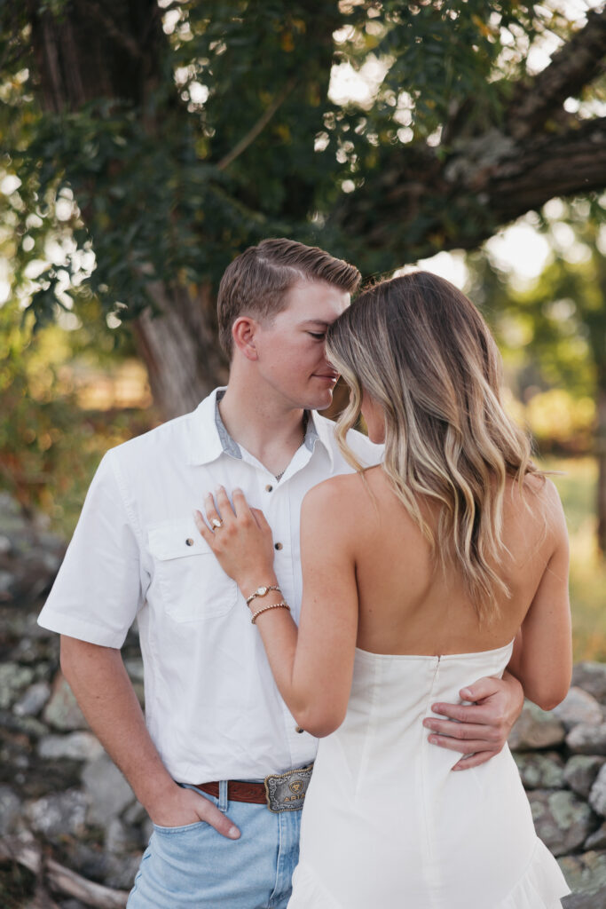 Refined western-style engagement outfit inspiration — white ruffled dress and boots for her, crisp shirt and denim for him