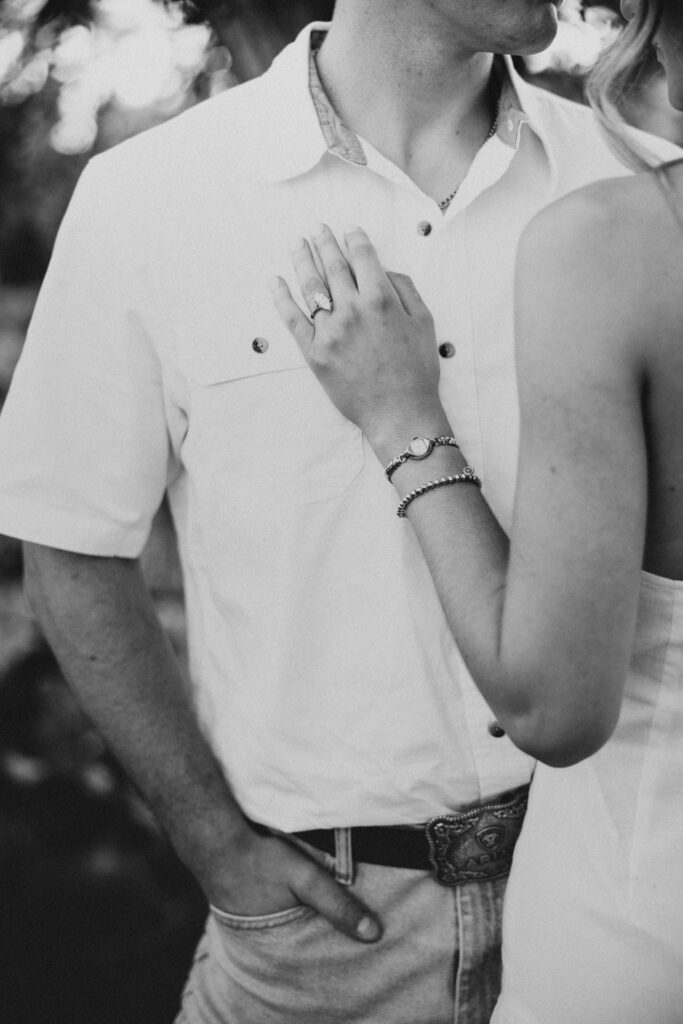 Refined western-style engagement outfit inspiration — white ruffled dress and boots for her, crisp shirt and denim for him