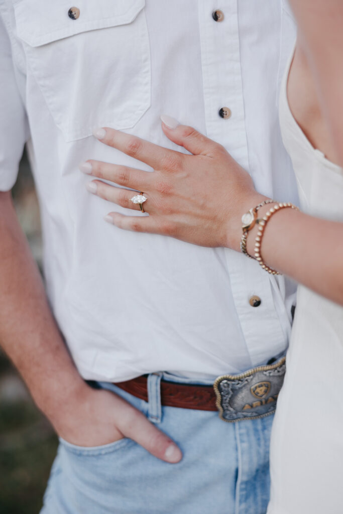 Refined western-style engagement outfit inspiration — white ruffled dress and boots for her, crisp shirt and denim for him