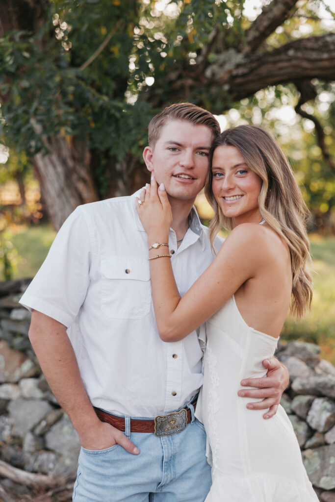 Refined western-style engagement outfit inspiration — white ruffled dress and boots for her, crisp shirt and denim for him