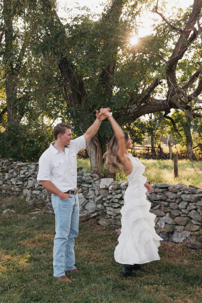 Golden-hour portrait of an engaged couple embracing in an open meadow, surrounded by warm natural light