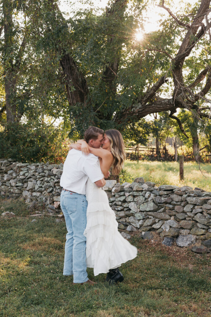 Golden-hour portrait of an engaged couple embracing in an open meadow, surrounded by warm natural light