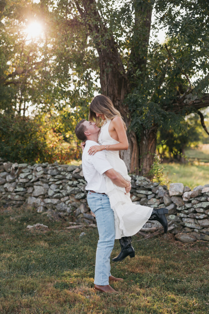 Golden-hour portrait of an engaged couple embracing in an open meadow, surrounded by warm natural light
