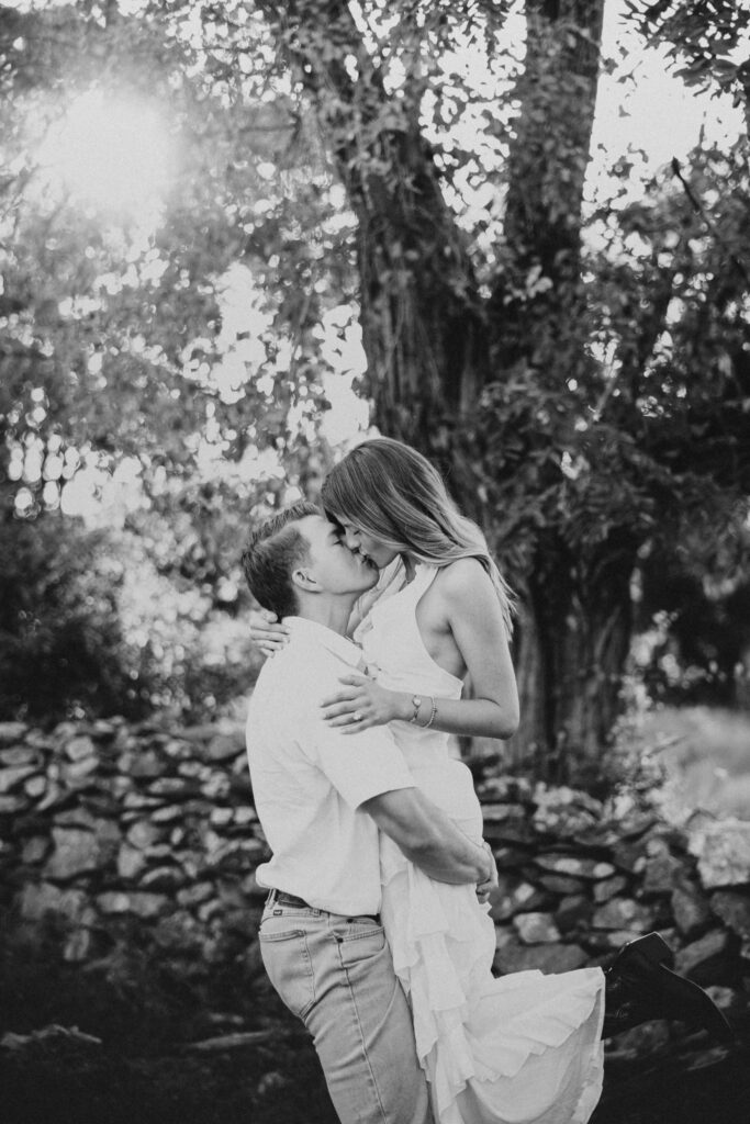 Golden-hour portrait of an engaged couple embracing in an open meadow, surrounded by warm natural light