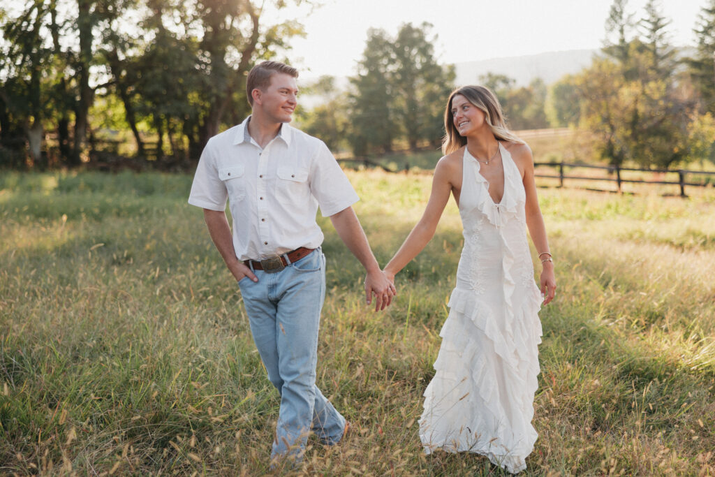 Sunset engagement photo of Olivia and Andrew holding hands in an open field — a timeless Virginia countryside moment.
