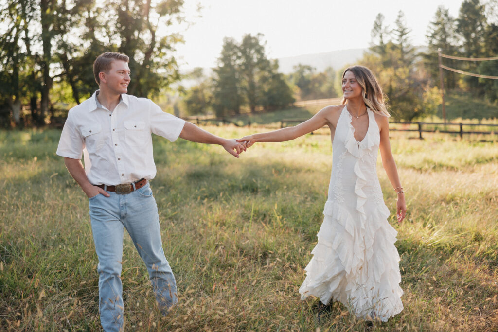 Sunset engagement photo of Olivia and Andrew holding hands in an open field — a timeless Virginia countryside moment.
