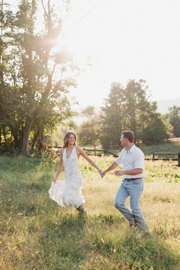 Golden-hour portrait of an engaged couple frolicking in an open meadow, surrounded by warm natural light.