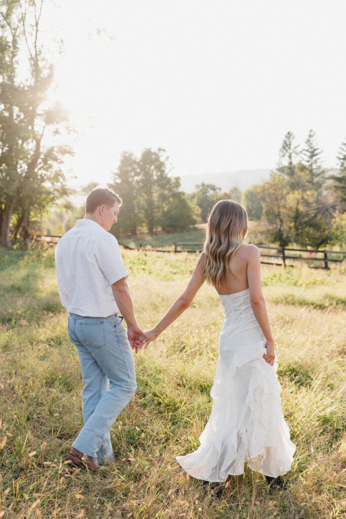 Golden-hour portrait of an engaged couple frolicking in an open meadow, surrounded by warm natural light.