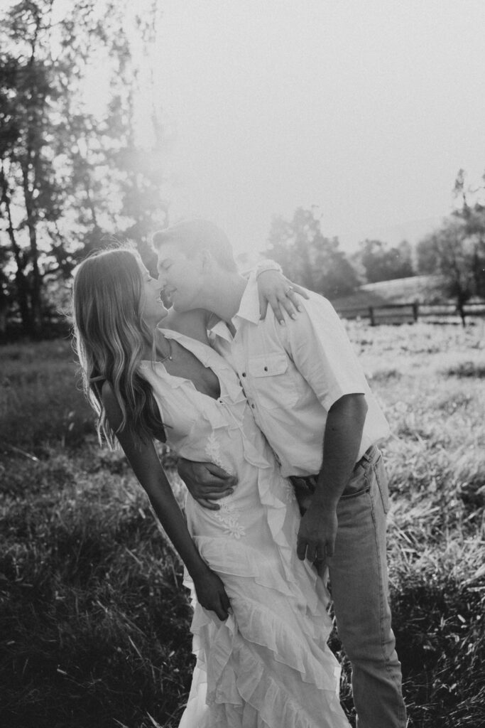 Golden-hour portrait of an engaged couple frolicking in an open meadow, surrounded by warm natural light.