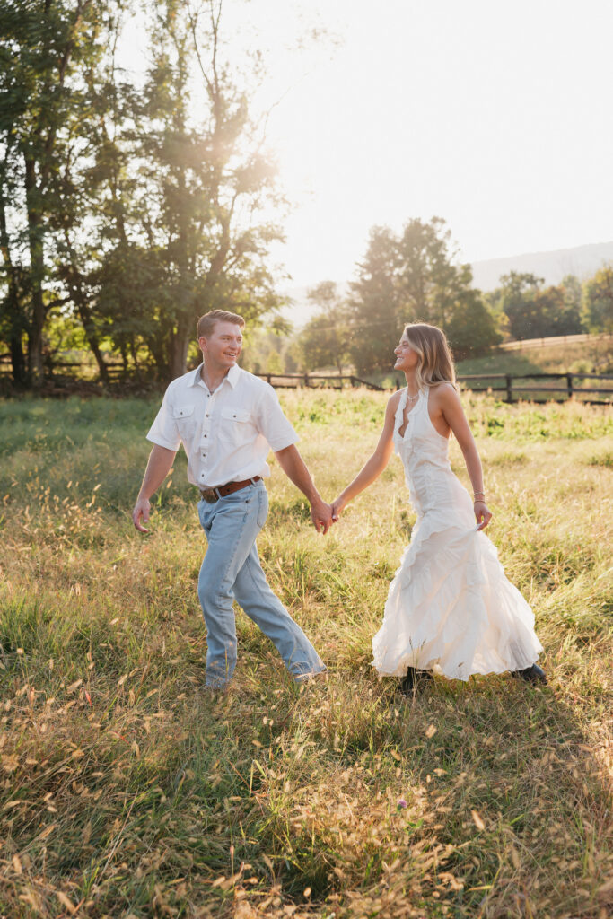 Golden-hour portrait of an engaged couple frolicking in an open meadow, surrounded by warm natural light.